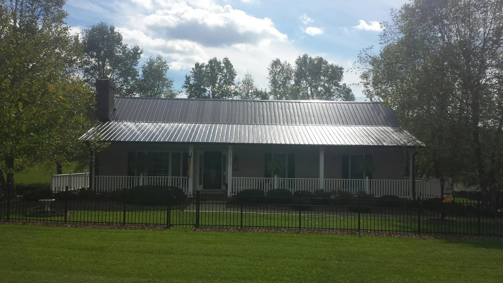 Gray metal roof on a brick ranch with a full width front porch — Gutter Guard Installation work by our crew in Rochester