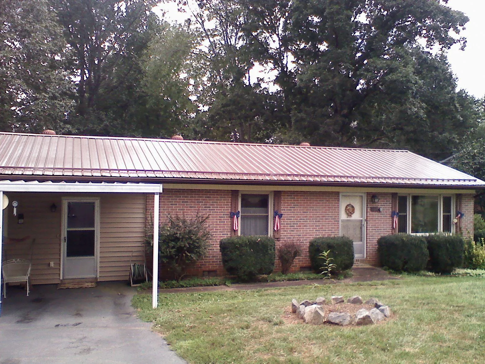 Bronze metal roof and carport on a brick ranch home — Roof Repair work by our crew in Rochester